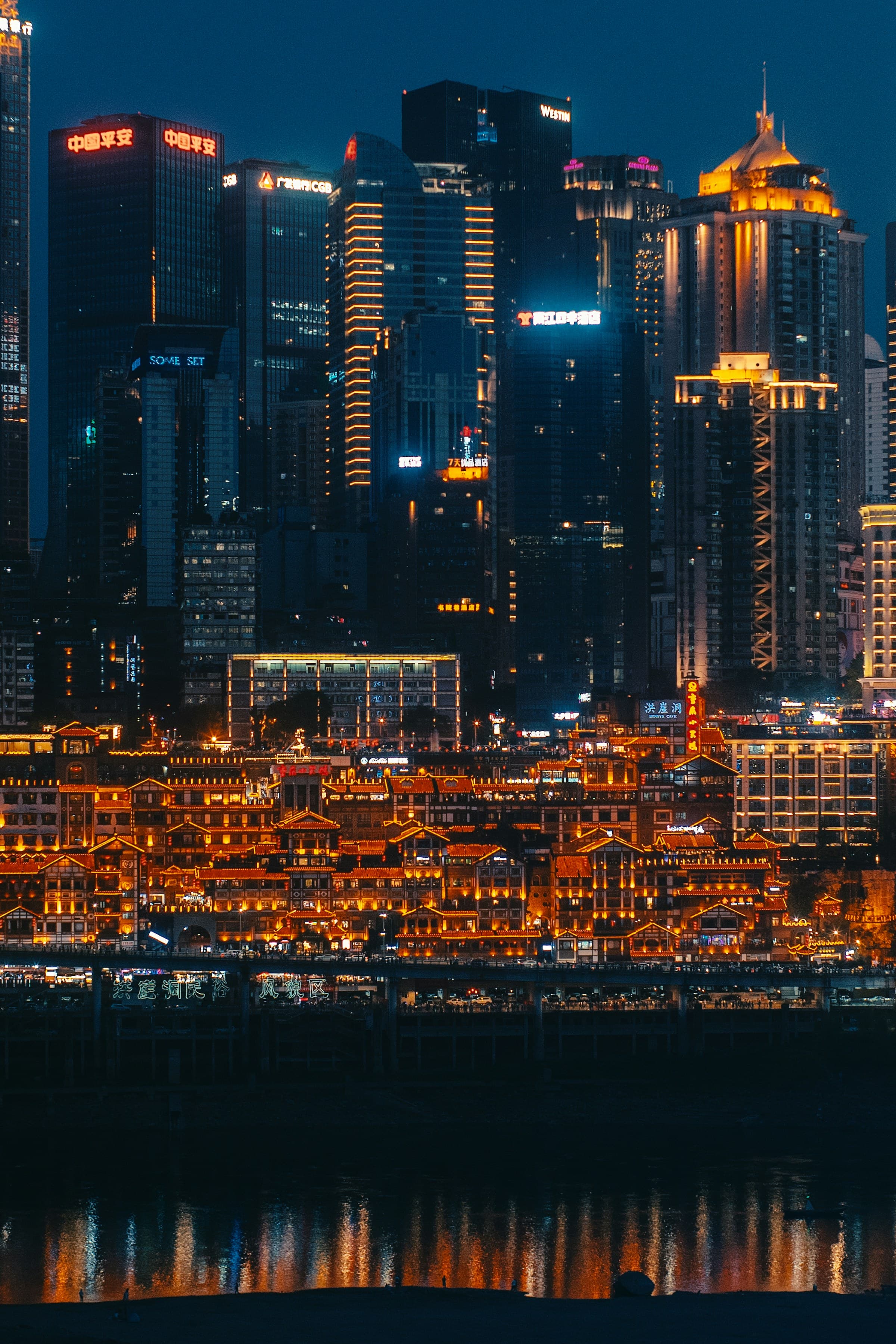Chongqing's illuminated riverfront layered beneath high-rise towers at night