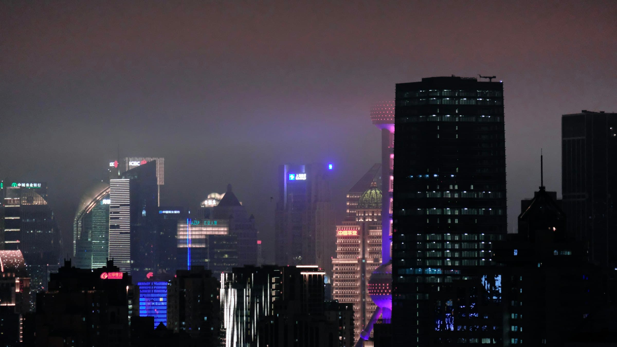 Shanghai skyscrapers glowing through purple night fog